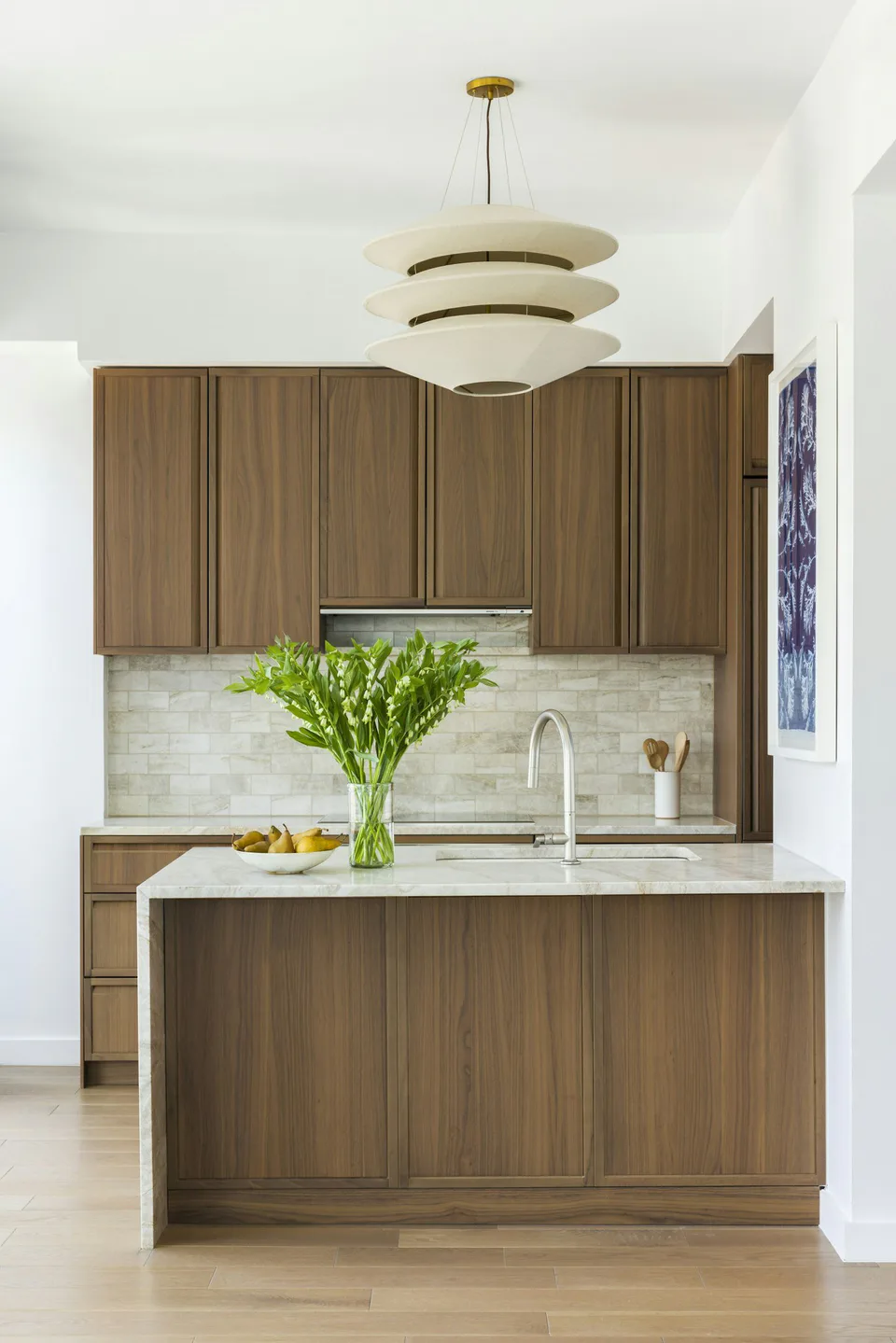 Typical kitchen with walnut cabinetry, a quartzite waterfall island and a tiered pendant at Midtown Luxury Residences, 30 East 31 Street, New York City, interior design by Alexandra Peck Design