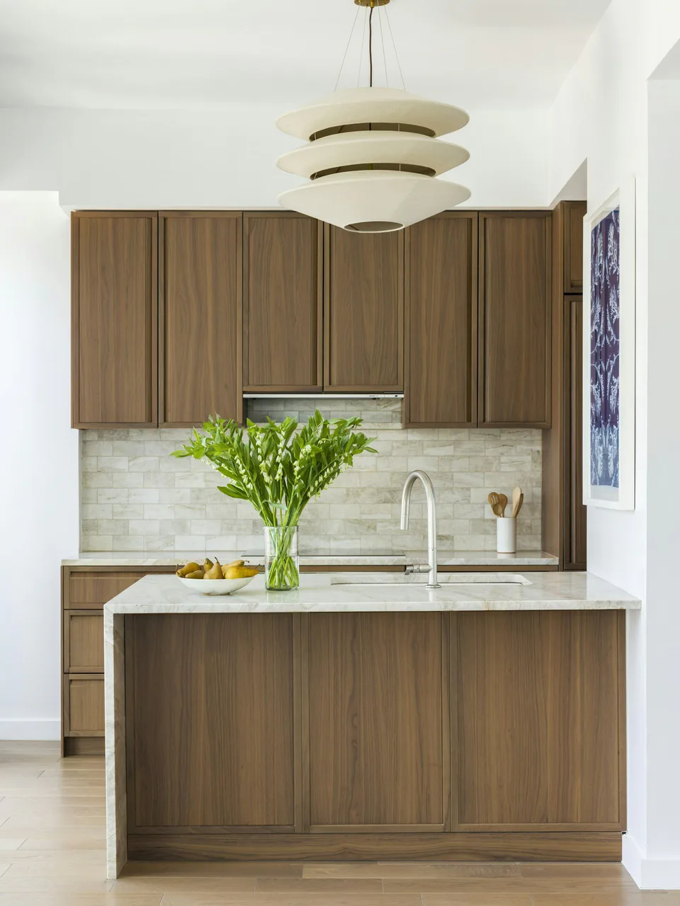 Typical kitchen with walnut cabinetry, a quartzite waterfall island and a tiered pendant at Midtown Luxury Residences, 30 East 31 Street, New York City, interior design by Alexandra Peck Design
