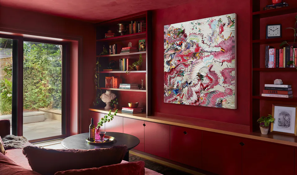 Color-drenched burgundy library with built-in shelves, a large abstract painting and a garden door at the Prospect Heights Brownstone, Brooklyn, interior design by Alexandra Peck Design, photography by Sarah Voigt