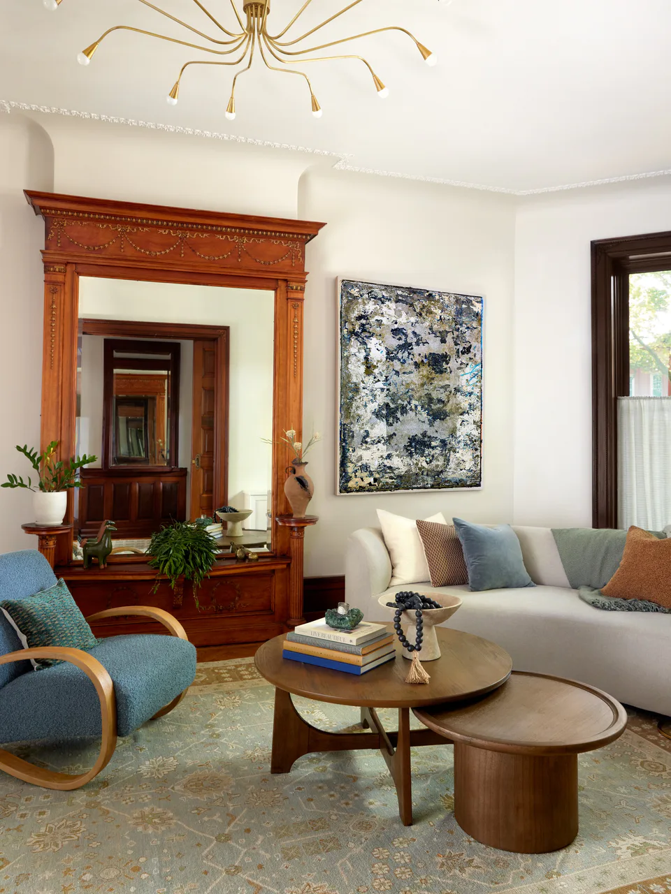 Parlor living room with the restored built-in mirror with ornate wood detailing, a bespoke brass chandelier and a custom curved Lazzoni sofa at the Prospect Heights Brownstone, Brooklyn, interior design by Alexandra Peck Design, photography by Sarah Voigt