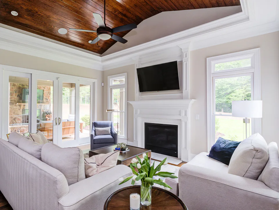 Family room with a wood-paneled tray ceiling, white fireplace, the clients’ sofas with new navy and ivory pillows and a polished nickel reading lamp at Durham Transitional, Durham, North Carolina, interior design by Alexandra Peck Design