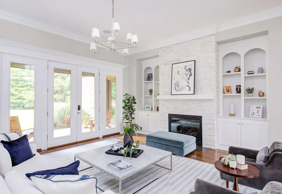 Living room with a white linen sofa, navy pillows, a marble coffee table and a white stone fireplace at Durham Transitional, Durham, North Carolina, interior design by Alexandra Peck Design