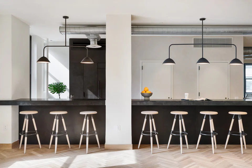 Pantry with blackened steel cabinetry, aged zinc countertops, wood and steel stools and black pendants on herringbone oak floors at Flatiron Workplace, 3 East 28th Street, New York City, interior design by Alexandra Peck Design