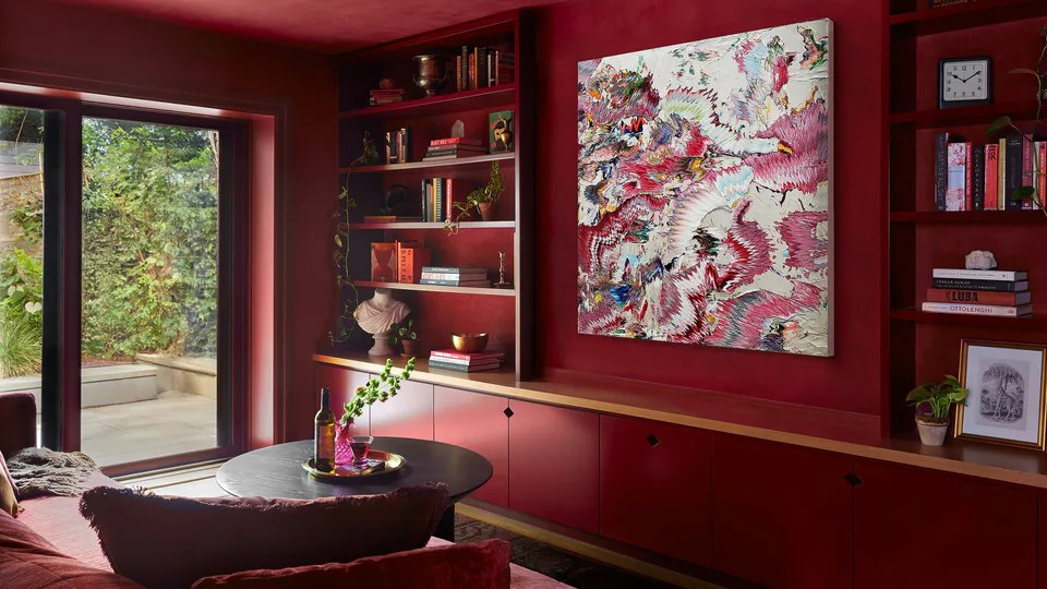 Color-drenched burgundy library with lime plaster walls and ceiling, lacquered built-in bookshelves, an original Robert Standish artwork and an aged brass saucer light at the Prospect Heights Brownstone, Brooklyn, New York, interior design by Alexandra Peck Design