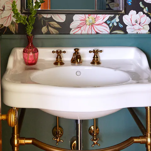 Detail of the console sink with vintage-inspired brass fixtures in the powder room at the Prospect Heights Brownstone, Brooklyn, New York, interior design by Alexandra Peck Design