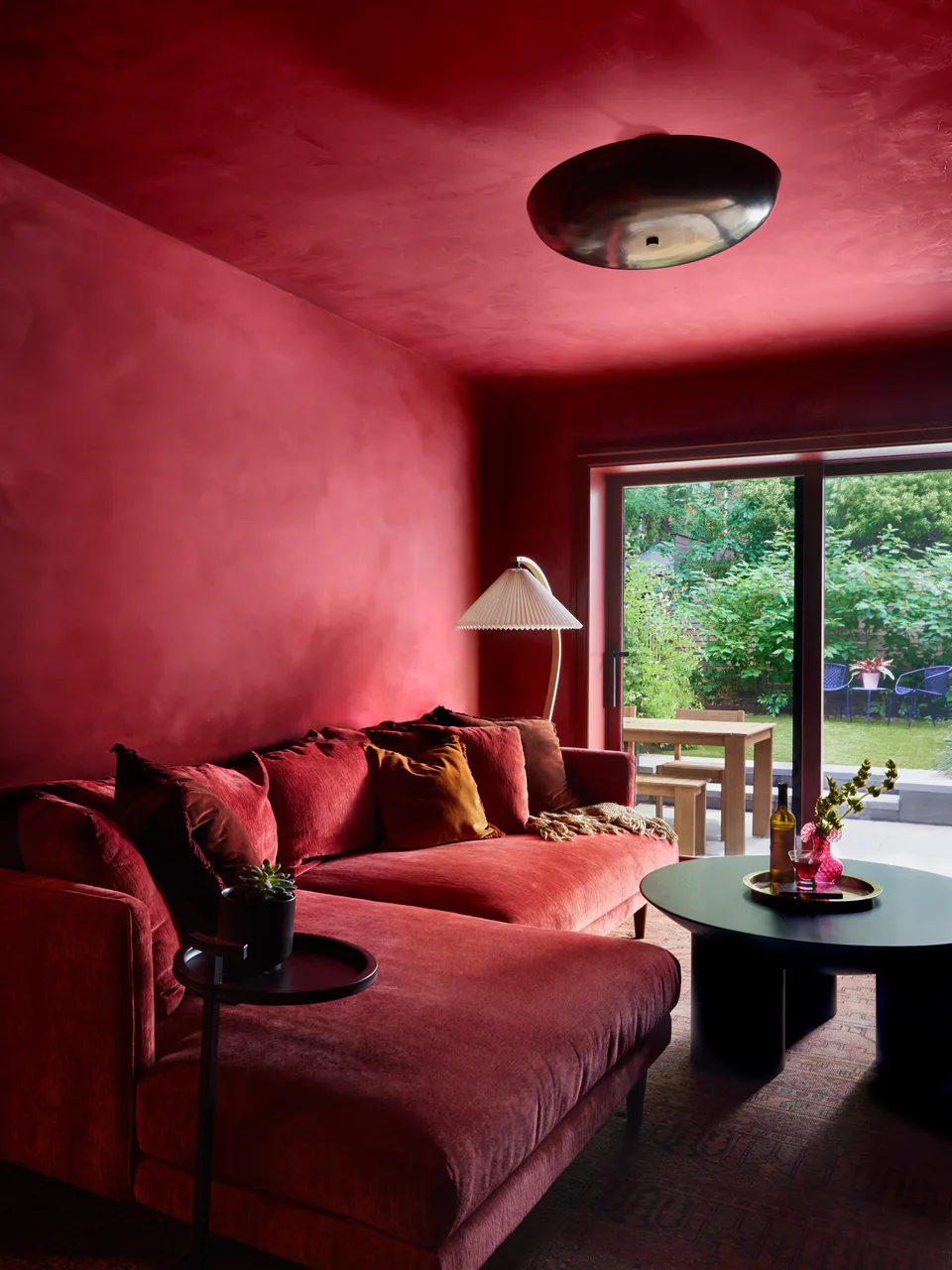 Burgundy chenille sectional and a black side table looking toward the garden doors in the color-drenched library at the Prospect Heights Brownstone, Brooklyn, New York, interior design by Alexandra Peck Design