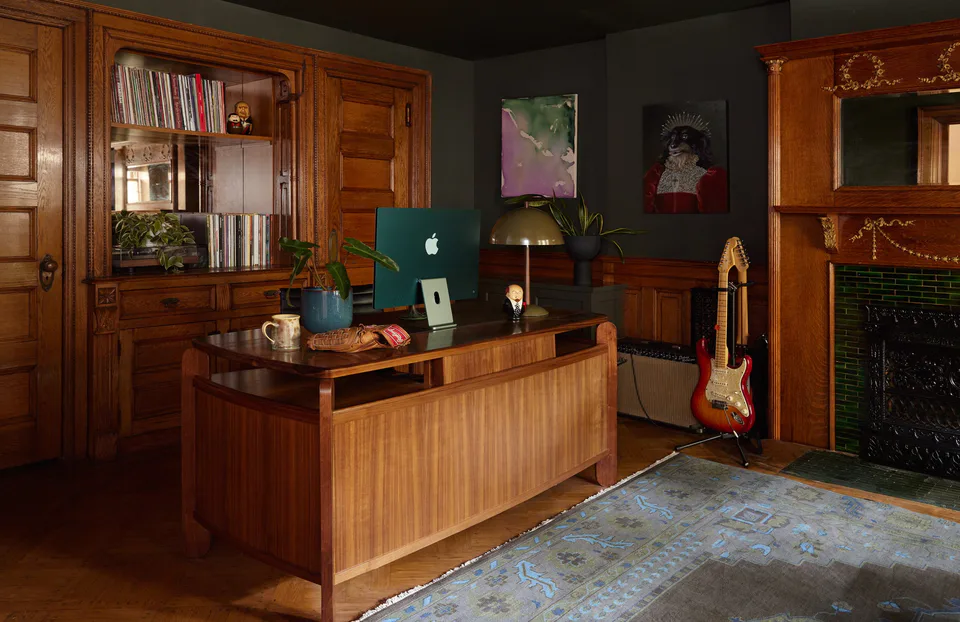 Moss-green study with a mid-century walnut desk, built-in bookcase, electric guitar and emerald-tiled fireplace at the Prospect Heights Brownstone, Brooklyn, New York, interior design by Alexandra Peck Design