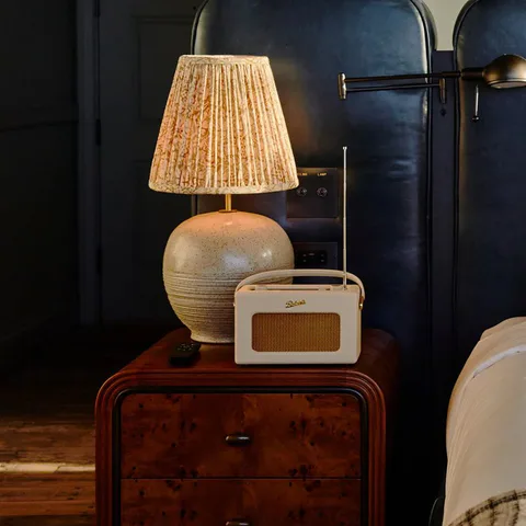 Detail: pleated table lamp and a radio on a burl bedside chest beside the blue leather headboard in the large bedroom at Soho House Nashville, Nashville, Tennessee, interior design by Alexandra Peck Design
