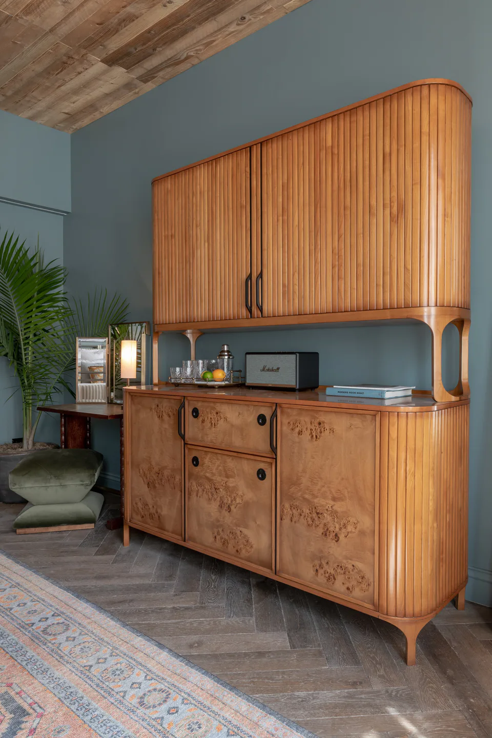 Fluted burl wood cabinet with a drinks shelf and radio against blue walls in a medium bedroom at Soho House Nashville, Nashville, Tennessee, interior design by Alexandra Peck Design