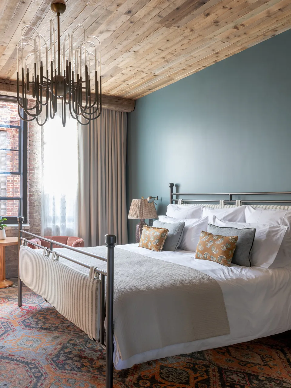 Medium bedroom with an iron bed, a sculptural chandelier, a timber ceiling and blue walls at Soho House Nashville, Nashville, Tennessee, interior design by Alexandra Peck Design