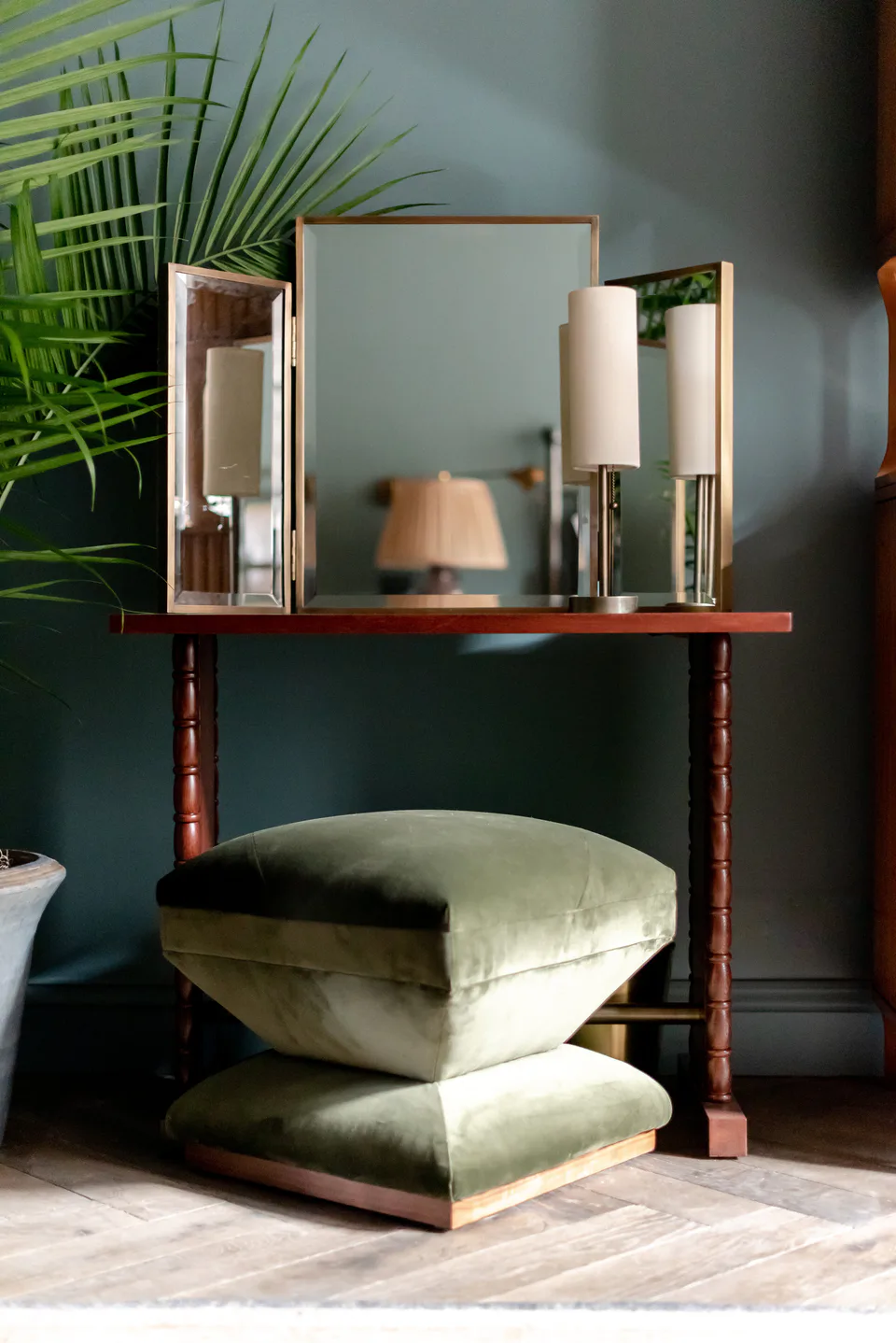 Dressing table with a triple mirror and a stacked green velvet ottoman in a medium bedroom at Soho House Nashville, Nashville, Tennessee, interior design by Alexandra Peck Design