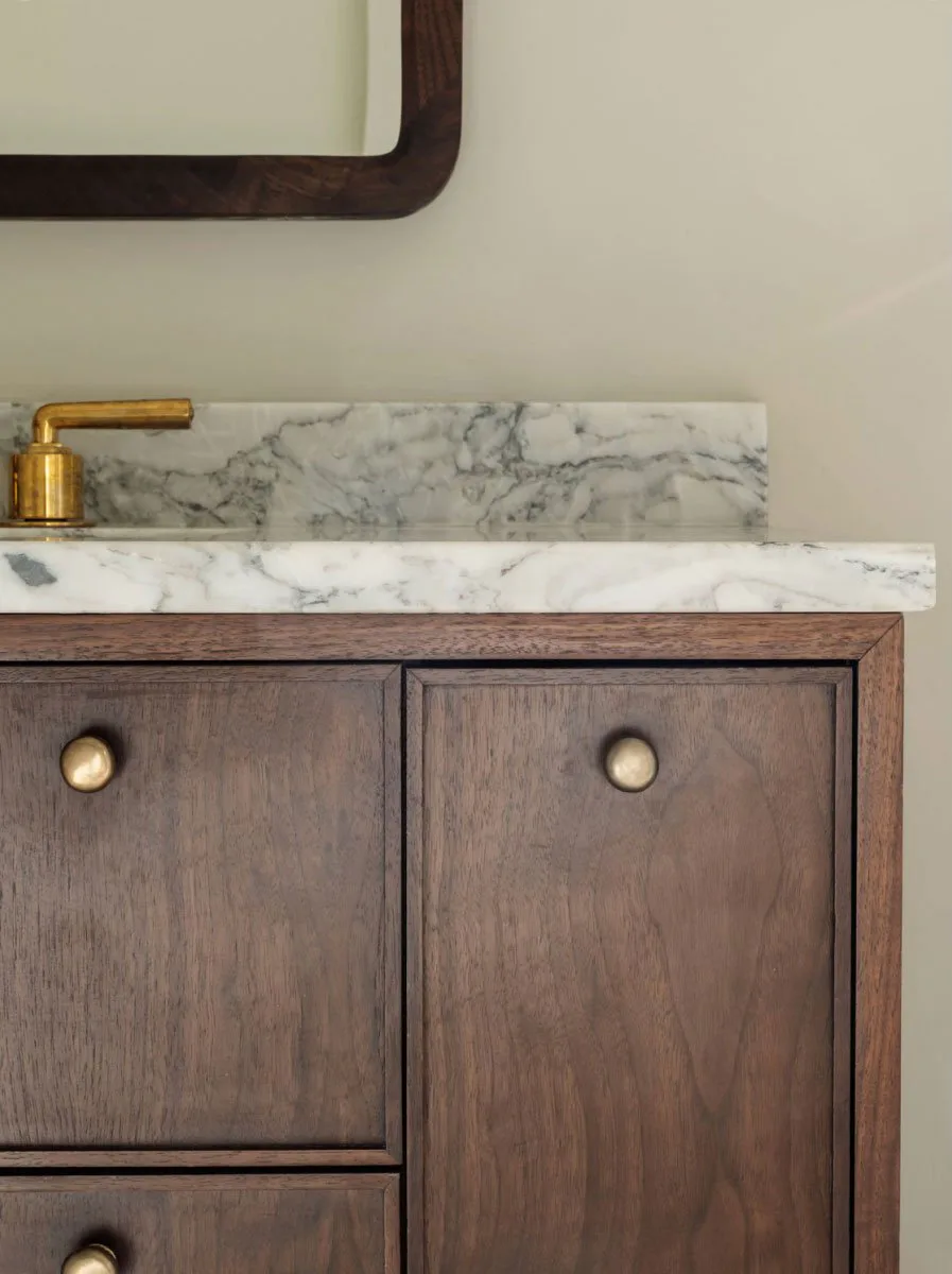 Walnut vanity with a marble top and an unlacquered brass tap at The Pinch Hotel, Charleston, South Carolina, interior design by Alexandra Peck Design