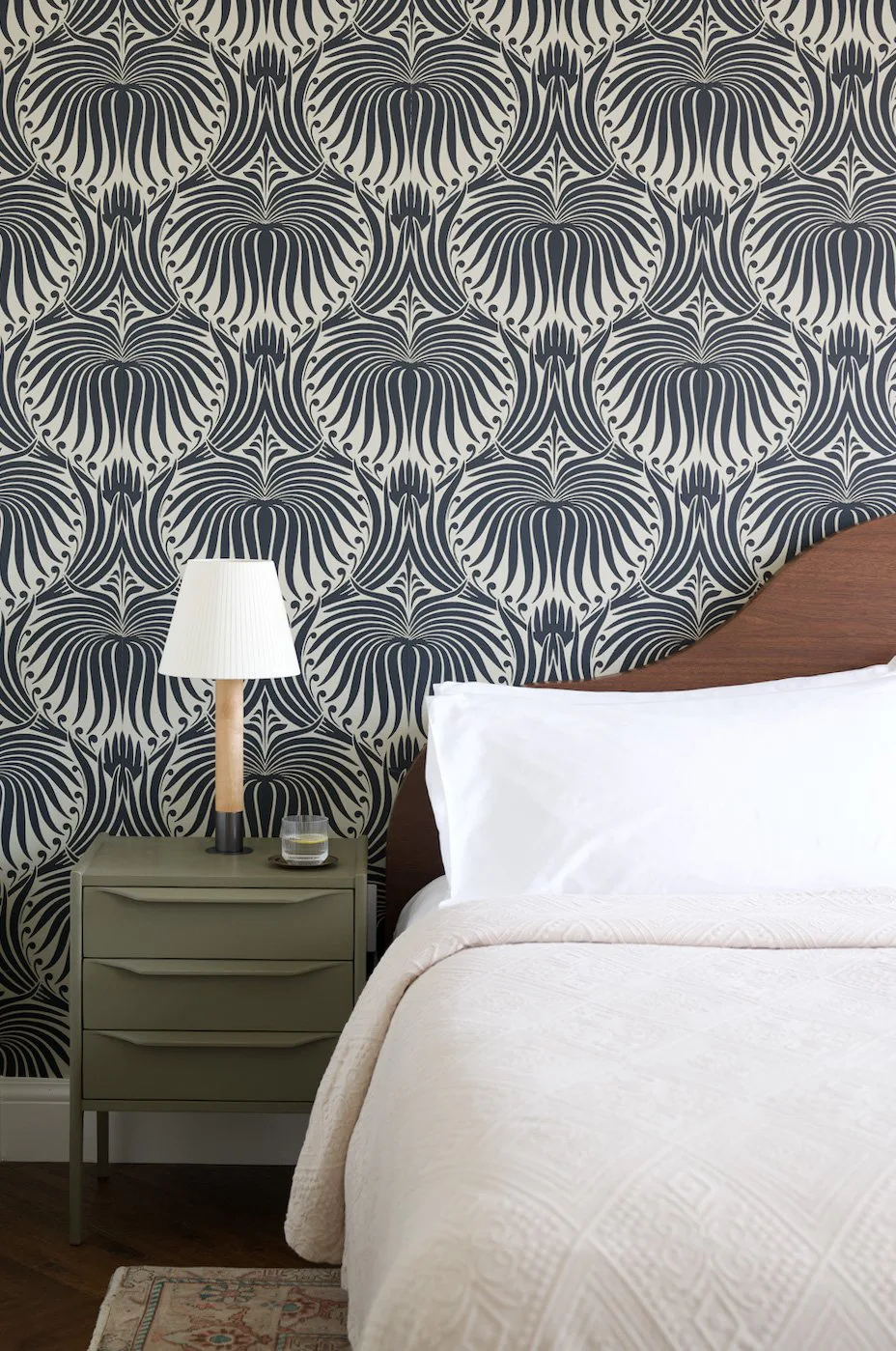 Bedroom with a graphic navy and white wallpaper, an olive bedside chest and white linen at The Pinch Hotel, Charleston, South Carolina, interior design by Alexandra Peck Design