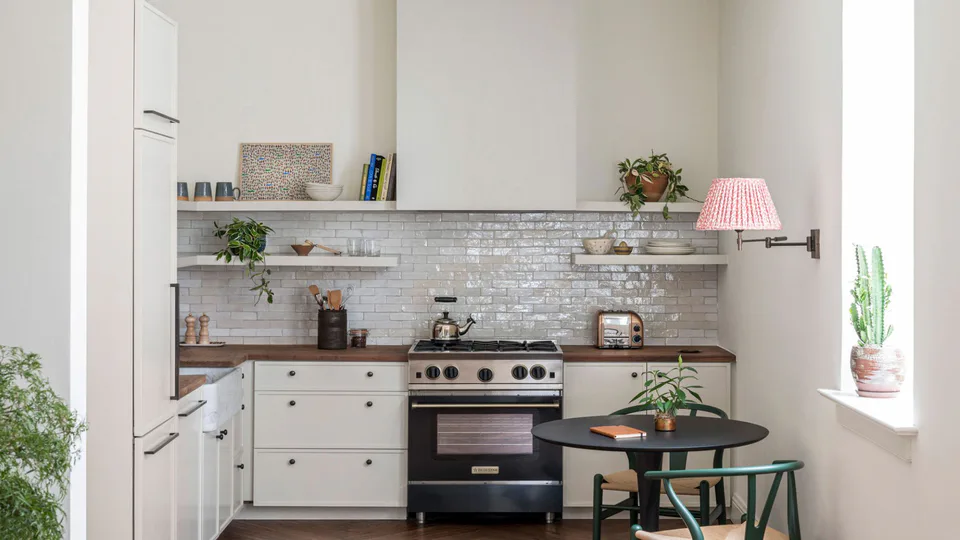 Kitchen with open shelving, a black range and a bistro table by the window at The Pinch Hotel, Charleston, South Carolina, interior design by Alexandra Peck Design