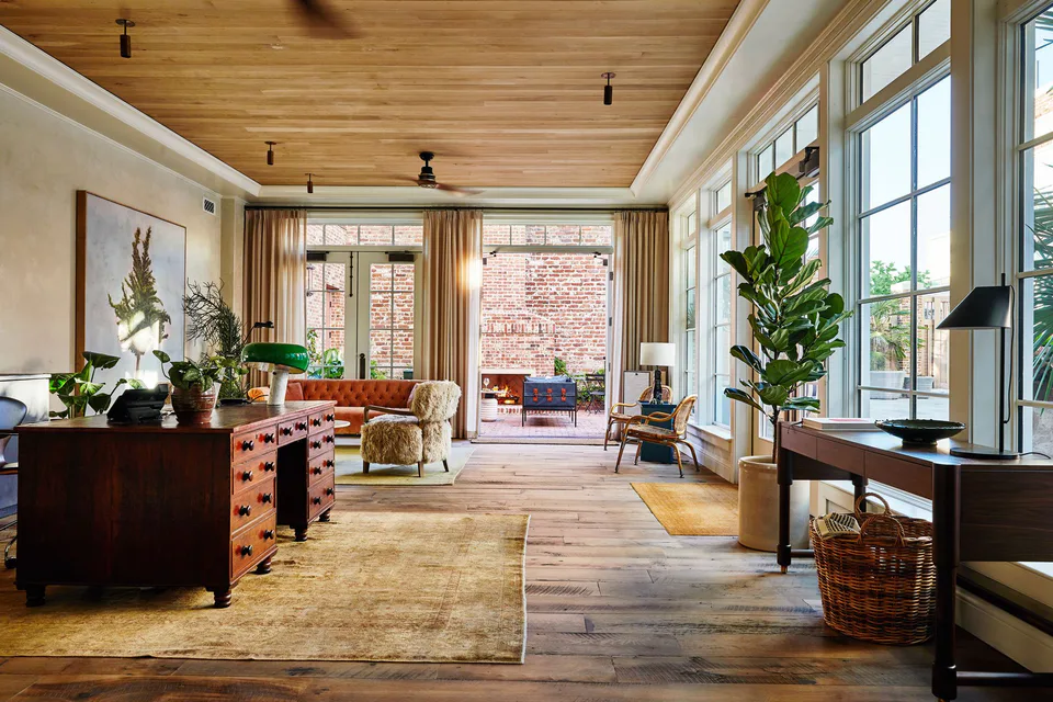 Long hotel lobby with an antique wooden chest, a timber ceiling and tall windows at The Pinch Hotel, Charleston, South Carolina, interior design by Alexandra Peck Design